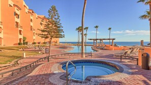 Ein Resort mit Swimmingpool, Liegestühlen, Palmen und Blick auf den Ozean.
