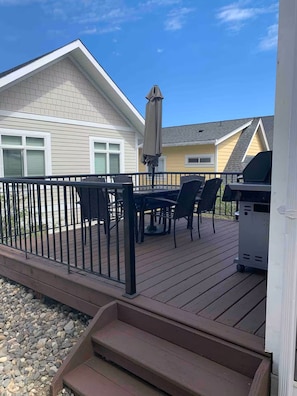 Una terraza con mesa y sillas, una parrilla y una zona cubierta con sombrilla.