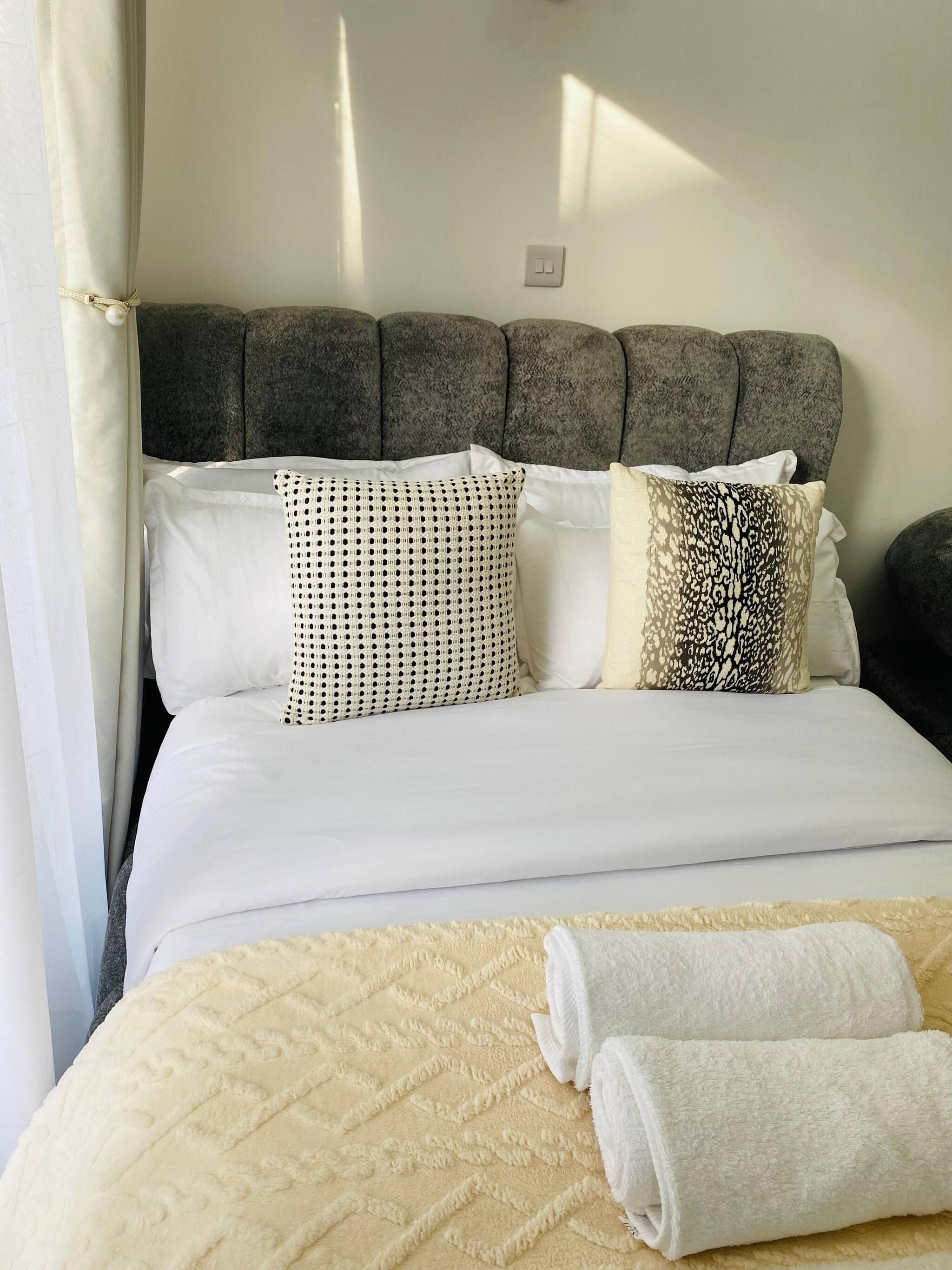 A bed with a headboard, pillows, and a blanket.