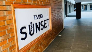 A corridor with a sign reading 'TSAVO SUNSET' on a brick wall.