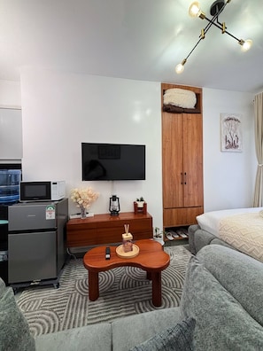 A compact living space with a flat-screen TV, a wooden cabinet, a sofa, a coffee table, and a ceiling light fixture. - Studio, Kiambu Road, Nairobi (Nairobi)