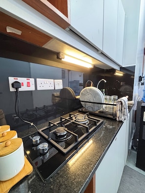 Una cocina con estufa a gas, un fregadero y un escurreplatos.