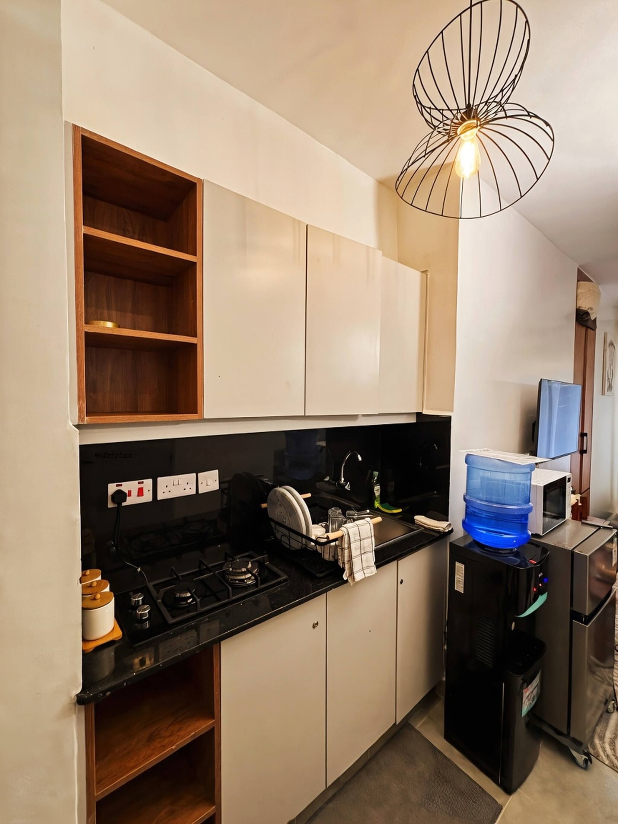 A compact kitchen with a gas stove, a microwave, and a water dispenser.