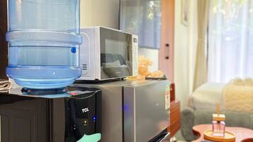 A compact kitchenette with a water dispenser, microwave, and a small refrigerator.