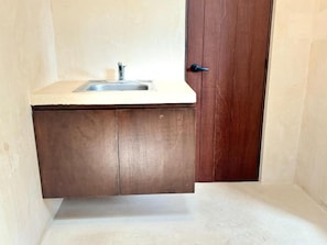 Een kleine badkamer met een wastafel, houten kastjes en een deur.