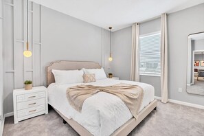 A neatly arranged bedroom with a bed, bedside tables, and a mirror. - Grand 15BR Kissimmee Estate 30 Guests (Kissimmee)