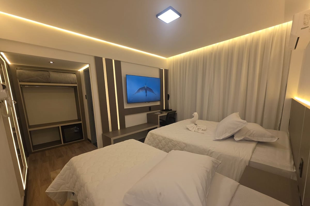 Habitación de hotel con dos camas, un televisor, un escritorio y un armario.