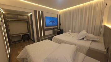 Habitación de hotel con dos camas, un televisor, un escritorio y un armario.