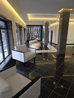 Um hall moderno com área de estar, balcão de recepção e vista para a rua.