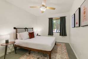 A bedroom with a bed, a bedside table, a lamp, a ceiling fan, a window with curtains, and framed artwork on the wall. - Backyard Oasis: Saltwater Pool + Pizza Oven (Tucson)