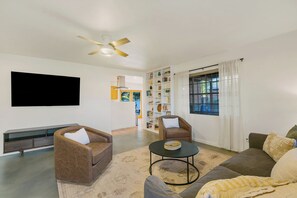Ein Wohnzimmer mit einem Flachbildfernseher, zwei braunen Ledersofas, einem Couchtisch und einem Bücherregal.