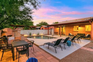 Ein Garten mit Pool, Sitzgelegenheit und Grill.