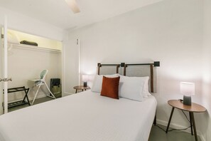 Ein Hotelzimmer mit einem Bett, Nachttischen, einem Sessel und einem Kleiderschrank.