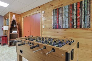 A room with a wooden foosball table, a red cabinet, and a wall-mounted colorful artwork. - The Sunrise Shack | Ellijay, GA (Gilmer County)