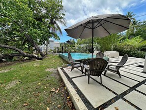 An outdoor patio with a pool, chairs, and an umbrella. - Modern 4 bedroom loft, open-air living, private pool and power generator (Cabo Rojo)