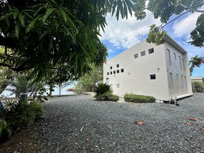 A building with a flat roof, rectangular windows, and a gravel driveway. - Modern 4 bedroom loft, open-air living, private pool and power generator (Cabo Rojo)
