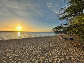 A beach with a sunset, clear sky, and a few people. - Modern 4 bedroom loft, open-air living, private pool and power generator (Cabo Rojo)