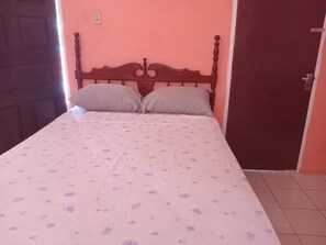 A single bed with a wooden headboard, two pillows, and a floral-patterned bedspread. - Port Antonio Residence House in Port Antonio (Port Antonio)