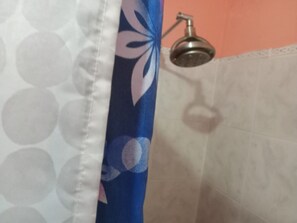 A bathroom with a shower, a white tiled wall, and a blue curtain with a floral pattern. - Port Antonio Residence House in Port Antonio (Port Antonio)