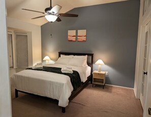 A bedroom with a bed, two bedside lamps, a ceiling fan, and two wall-mounted paintings. - Relaxing & Peaceful San Antonio Home (San Antonio)