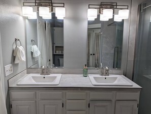 Une salle de bain avec deux lavabos, un grand miroir et un espace douche.