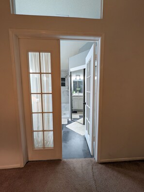 A hallway leading to a bathroom with a shower and a sink. - Relaxing & Peaceful San Antonio Home (San Antonio)