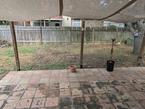 A patio area with a wooden fence, a potted plant, and a brick floor. - Relaxing & Peaceful San Antonio Home (San Antonio)