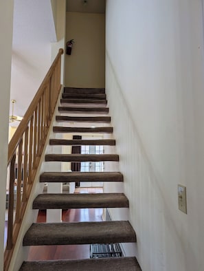 A carpeted staircase with wooden railings leading to a door with a window. - Relaxing & Peaceful San Antonio Home (San Antonio)