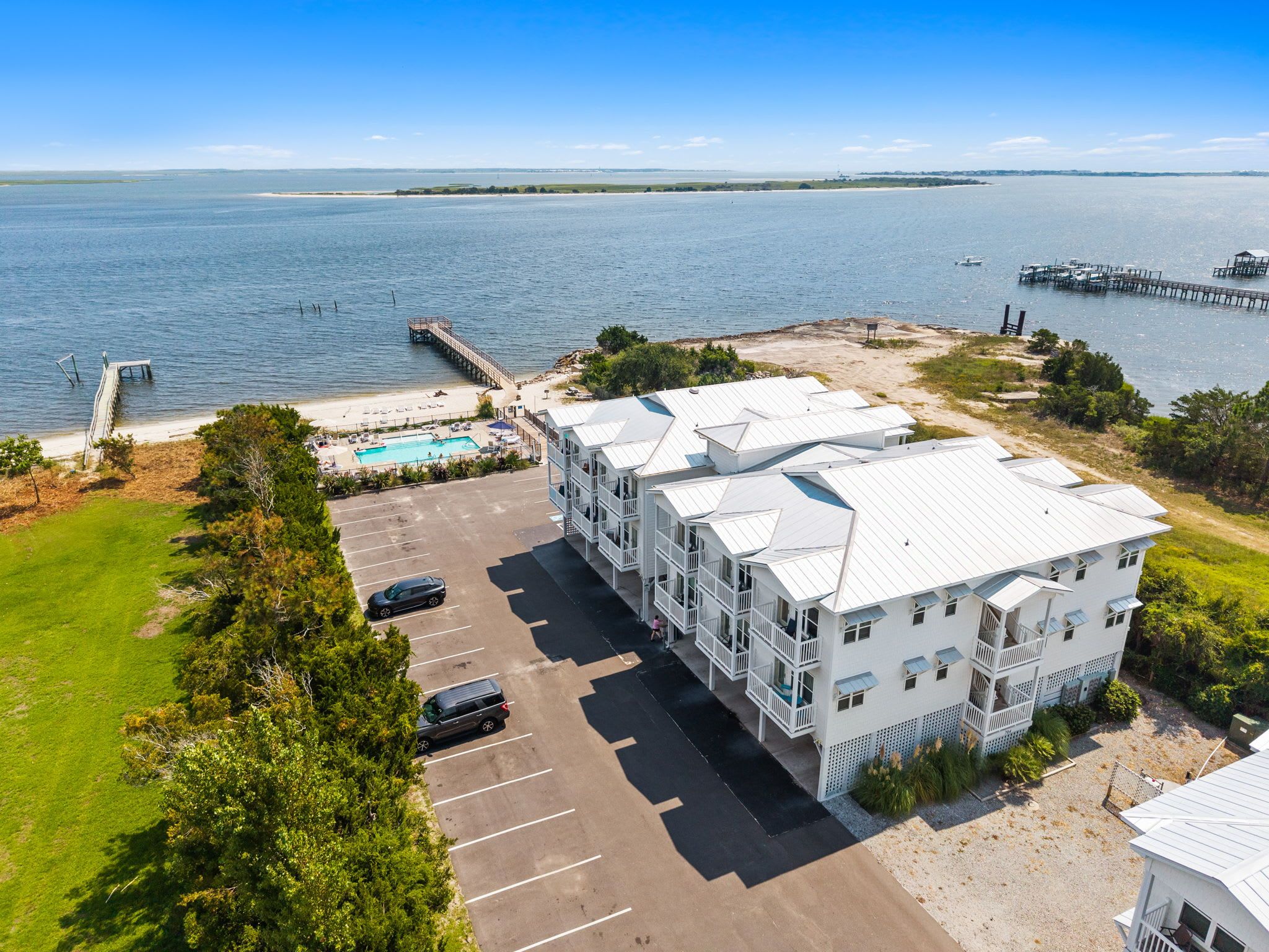 A coastal hotel with a swimming pool, parking, and a view of the sea.