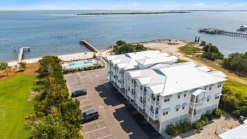 A coastal hotel with a swimming pool, parking, and a view of the sea.