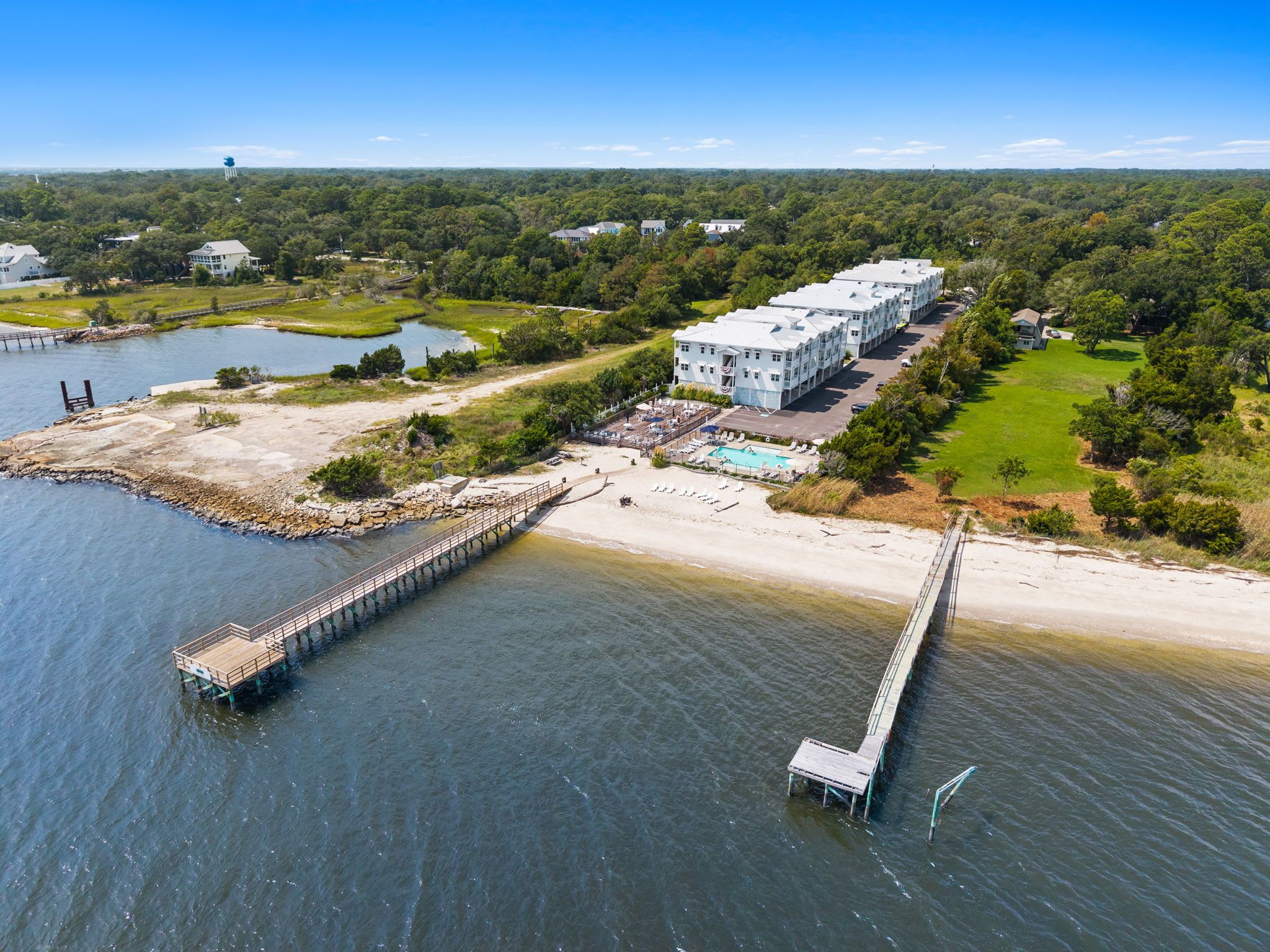 A coastal hotel with a pier, a swimming pool, and a large building with multiple balconies.