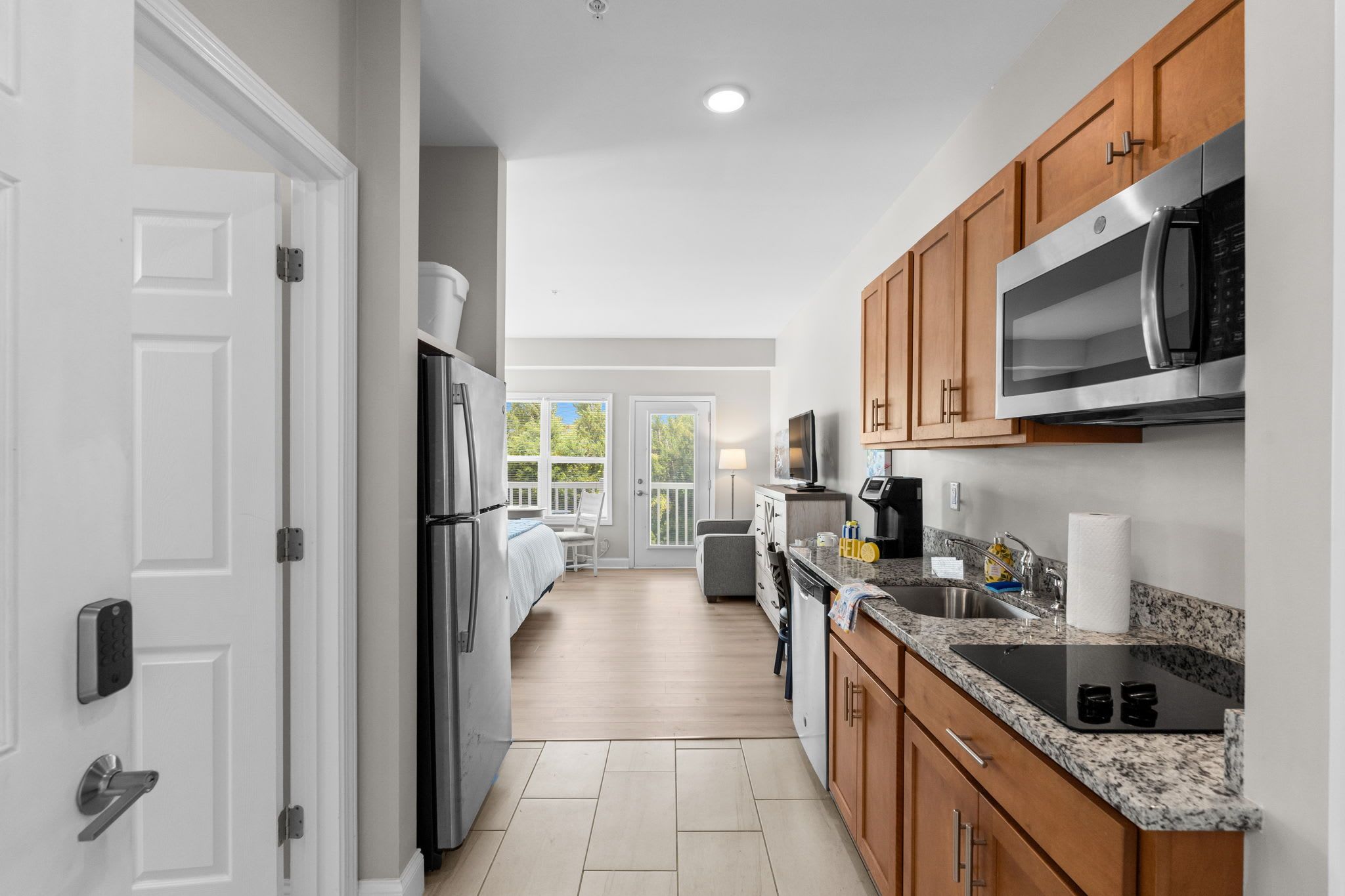 A modern kitchen with stainless steel appliances, wooden cabinets, and a granite countertop.