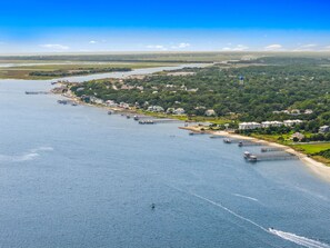 Une ville côtière dotée d’un port de plaisance, de maisons situées au bord de l’eau et d’un pont visible au loin.