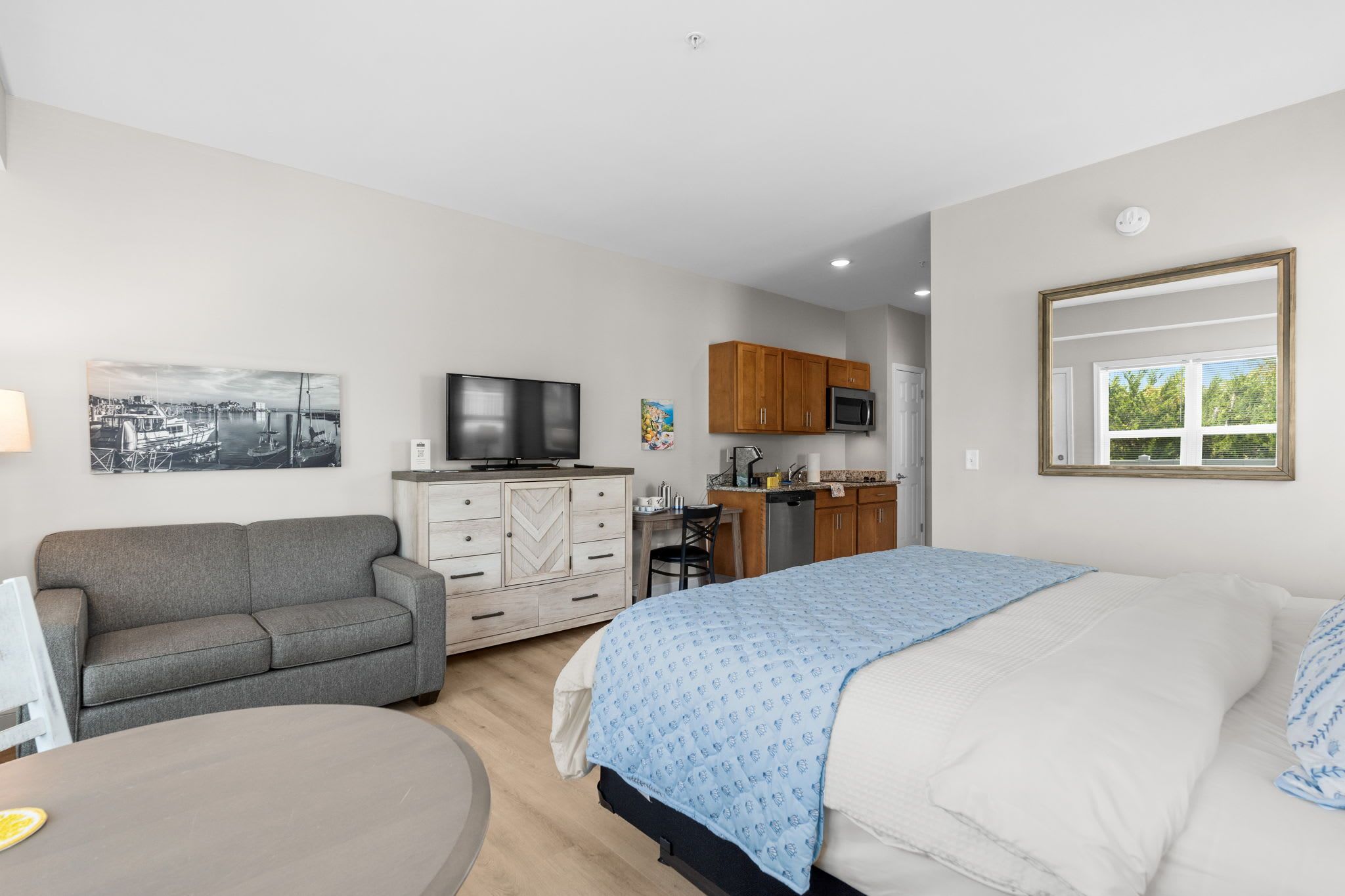 Un dormitorio con cama, sofá, televisión, kitchenette y zona de comedor.