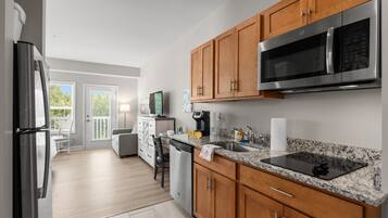 A modern kitchen with wooden cabinets, a stainless steel refrigerator, a microwave, and a granite countertop.