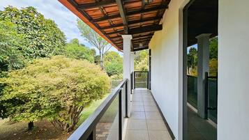 Varanda coberta com vista para um jardim e árvores.