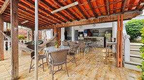 An outdoor patio with wicker furniture, a tiled floor, and a kitchen area in the background. - Casa com Piscina e Sauna no Granja Vista Alegre (Contagem)