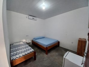 A small, single-room accommodation with two beds, a wooden wardrobe, and a small desk. - Pousada do Beto (Barreirinhas)