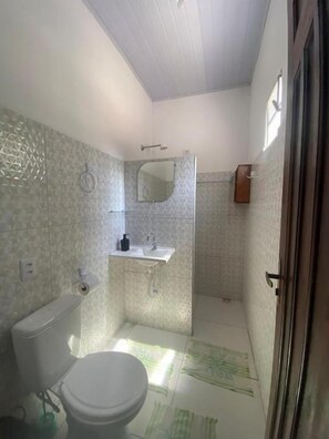 A small bathroom with a toilet, sink, and shower area. - Pousada do Beto (Barreirinhas)