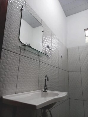 A bathroom with a sink, mirror, and shower. - Pousada do Beto (Barreirinhas)