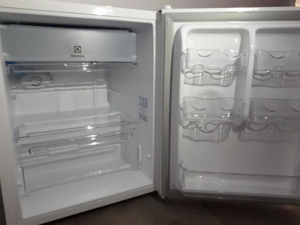 An open refrigerator with clear shelves and a water dispenser.