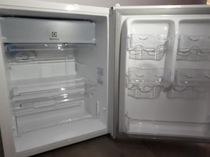 Un refrigerador abierto con repisas transparentes y un dispensador de agua.