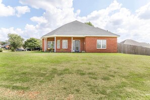 A single-story brick house with a front porch, a fenced yard, and a clear sky. - Casa Oasis Bonaire · 3 Kings · Fireplace · Gym (Bonaire)