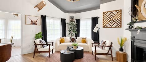 A modern living room with a fireplace, a round coffee table, and a sofa with cushions.