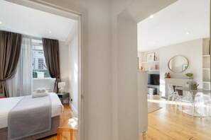 A modern hotel room with a bed, bedside table, and a view of the city. - HR2 - Charming 1-Bed near Holland Park (London)