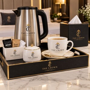 Una bandeja amb una cafetera, una tassa de cafè, una caixa de Nescafé Classic, un pot de sucre moreno i un petit recipient amb tapa, tot amb el logotip de 'The Crown Hotel'.