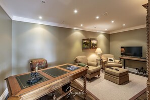 A well-lit living room with a wooden coffee table, a sofa, a TV, and a fireplace. - 7 bed 9 bath cottage and boathouse on Lake Muskoka, SW exposure! (Port Carling)