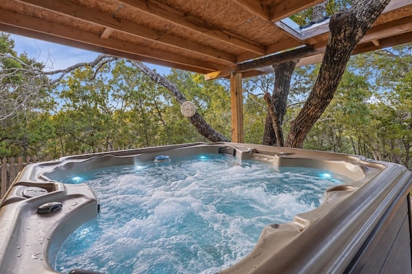 Un jacuzzi con estructura de madera sobre él, rodeado de árboles.