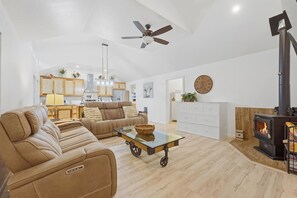 Un vaste espace de vie comprenant un canapé, une table basse, une cheminée et, au fond, une cuisine.