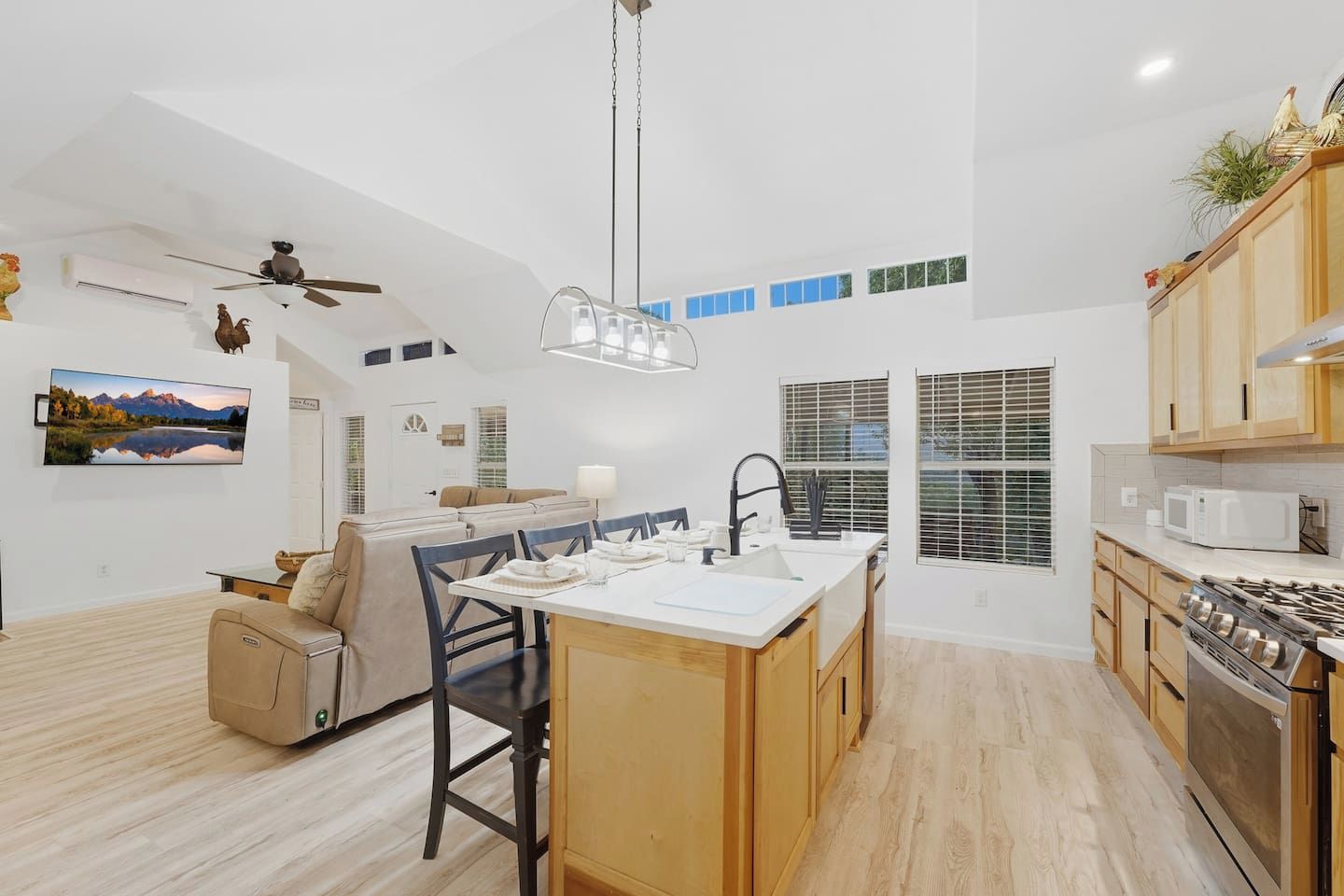 Une cuisine moderne dotée d’un îlot central, d’un coin repas avec un canapé et d’un ventilateur de plafond.